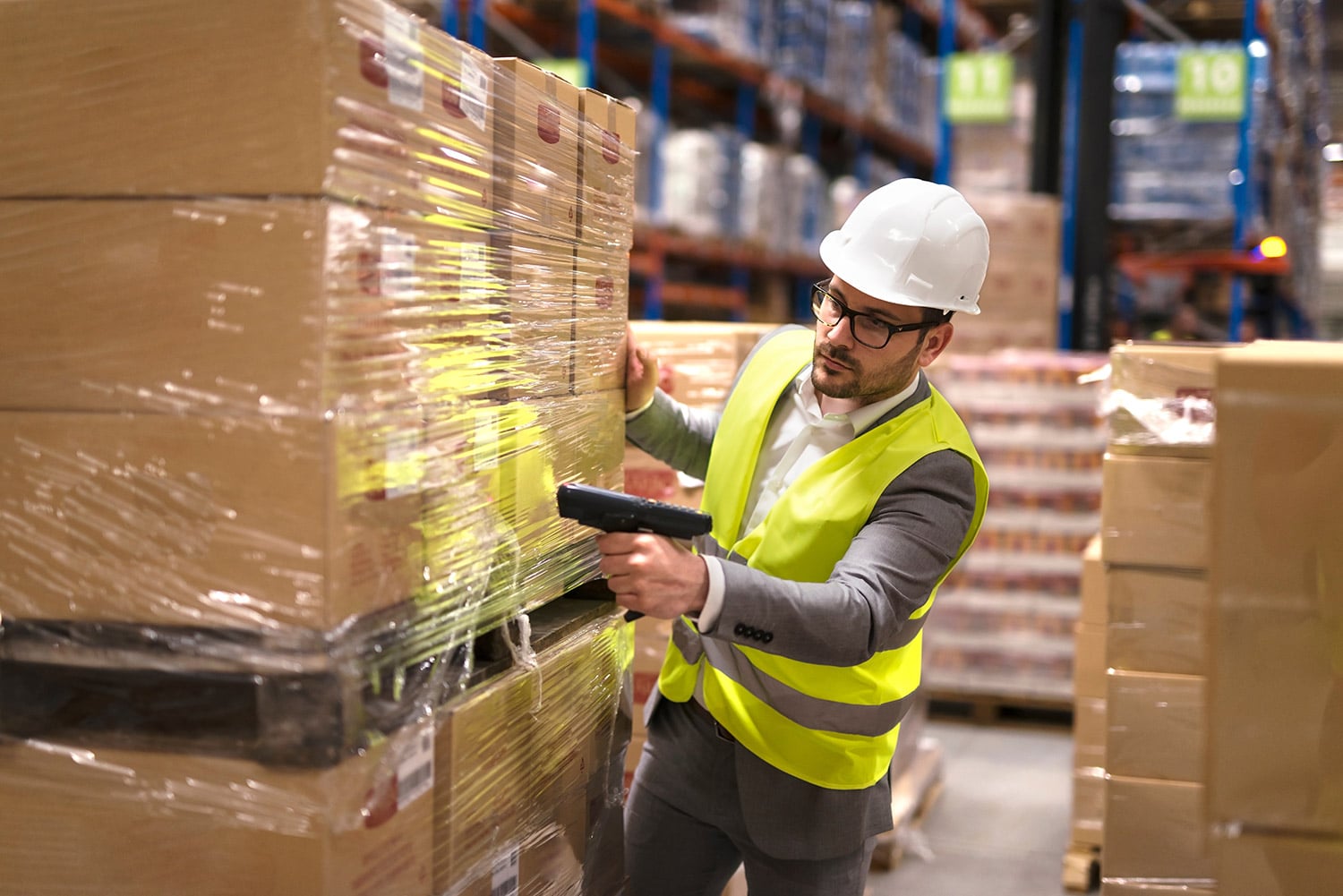 Man in warehouse scanning packages with vest and hard hat