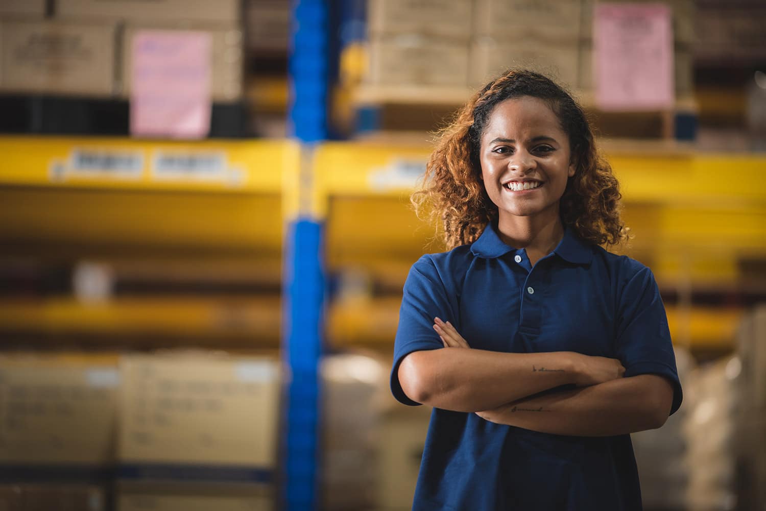 Smiling woman with arms folded standing in warehouse