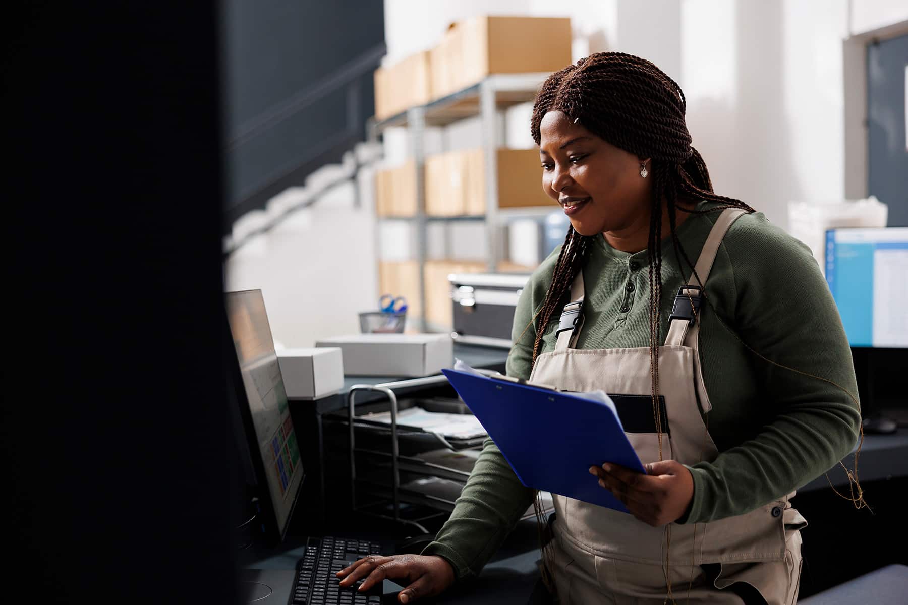 smiling supply chain manager working on computer is stockroom 